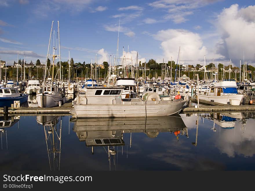 An old fishing boat at a marina full of yachts