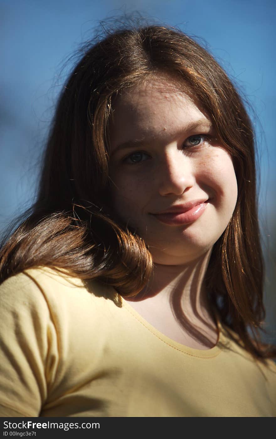 Young girl with long brown hair smiling and tilting her head