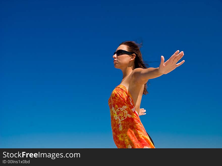 View from side of woman standing on the beach wearning orange pareo placed on the sky. View from side of woman standing on the beach wearning orange pareo placed on the sky