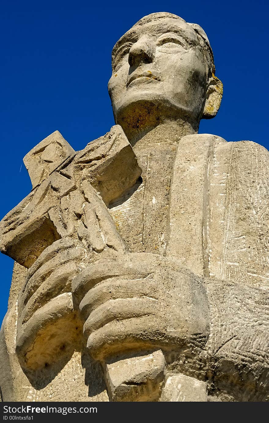 Stone statue of a priest with a cross in his hands. Stone statue of a priest with a cross in his hands