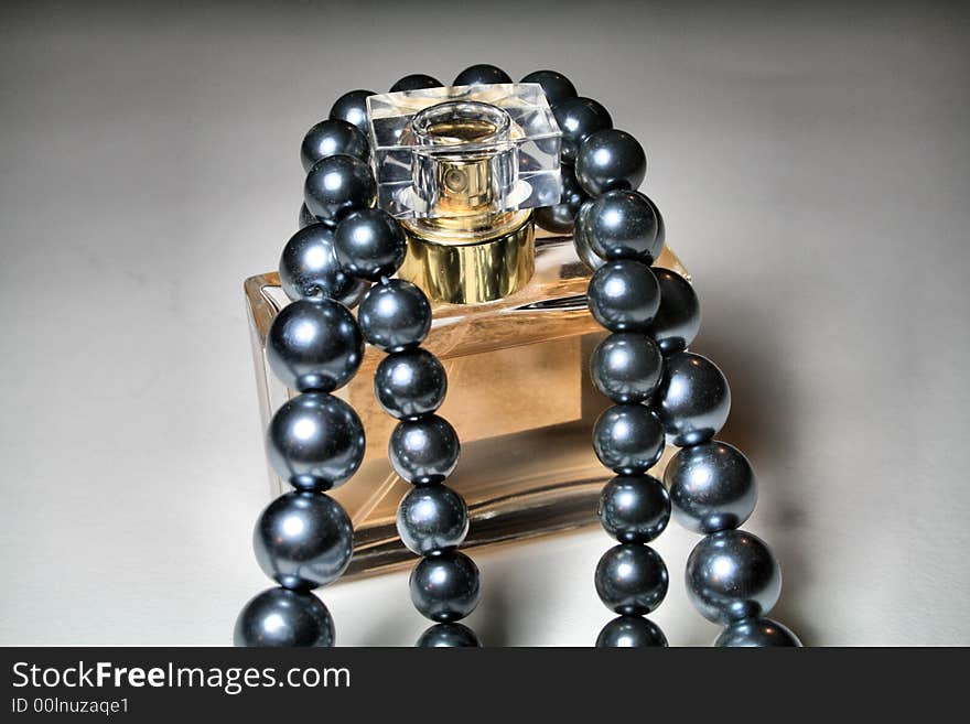 Black tahitian pearls draped over a bottle of perfume. Black tahitian pearls draped over a bottle of perfume