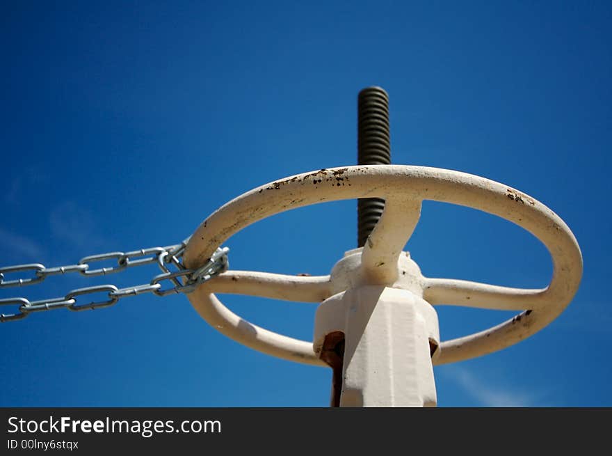 Chained Industrial Wheel  on a Deep Blue Sky. Narrow depth of field.