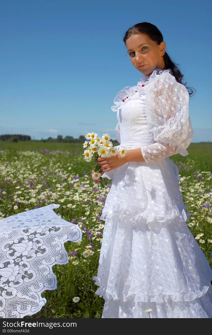 Beautiful young woman, in a white dress under a white umbrella with camomiles, in a field