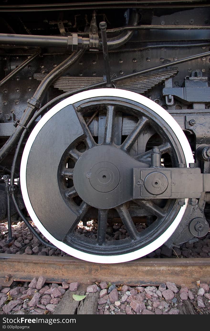 An antique steam engine's wheel sitting on a piece of track. An antique steam engine's wheel sitting on a piece of track