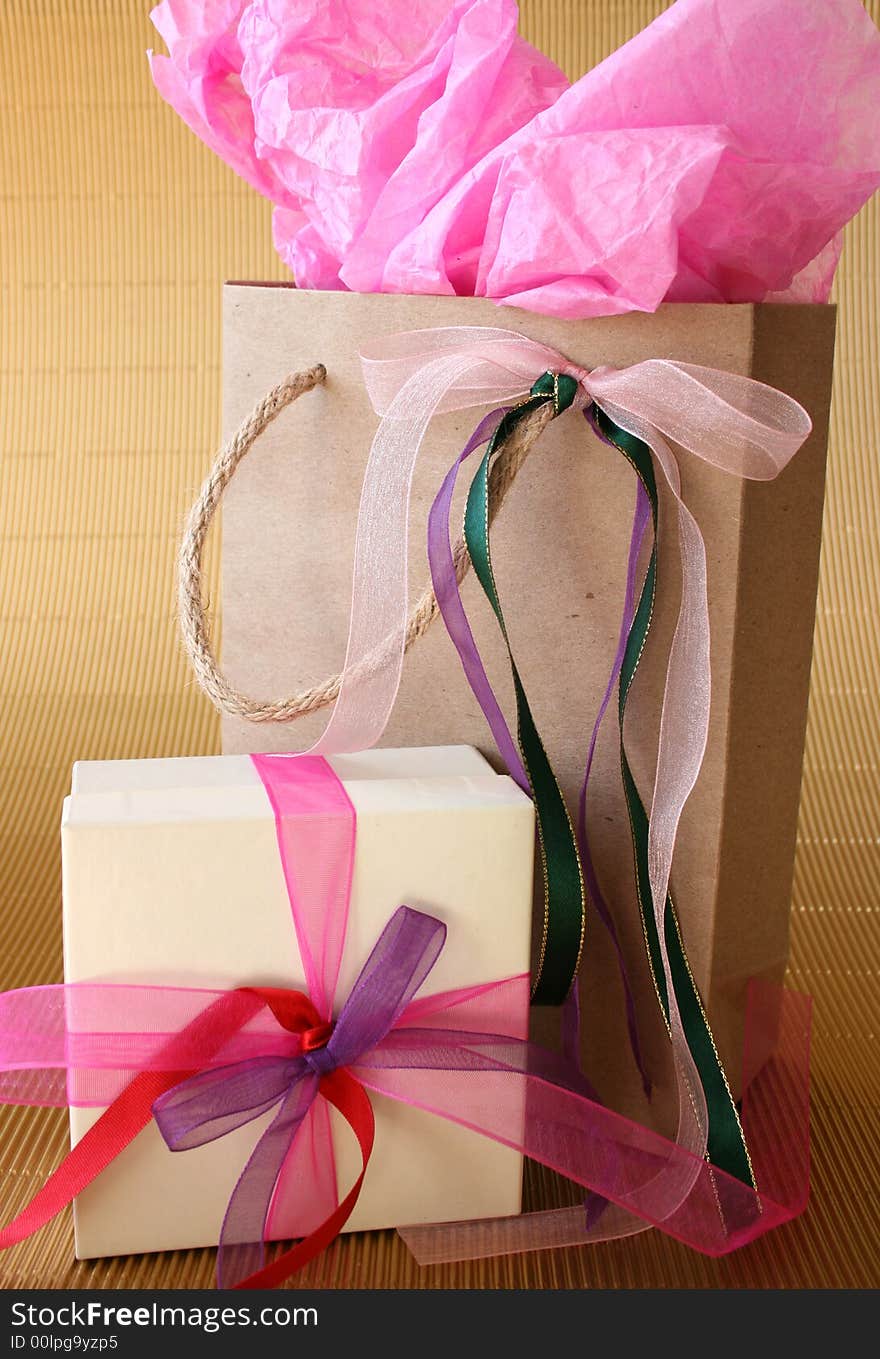 Cream colored gift box and brown gift bag with ribbons. Cream colored gift box and brown gift bag with ribbons