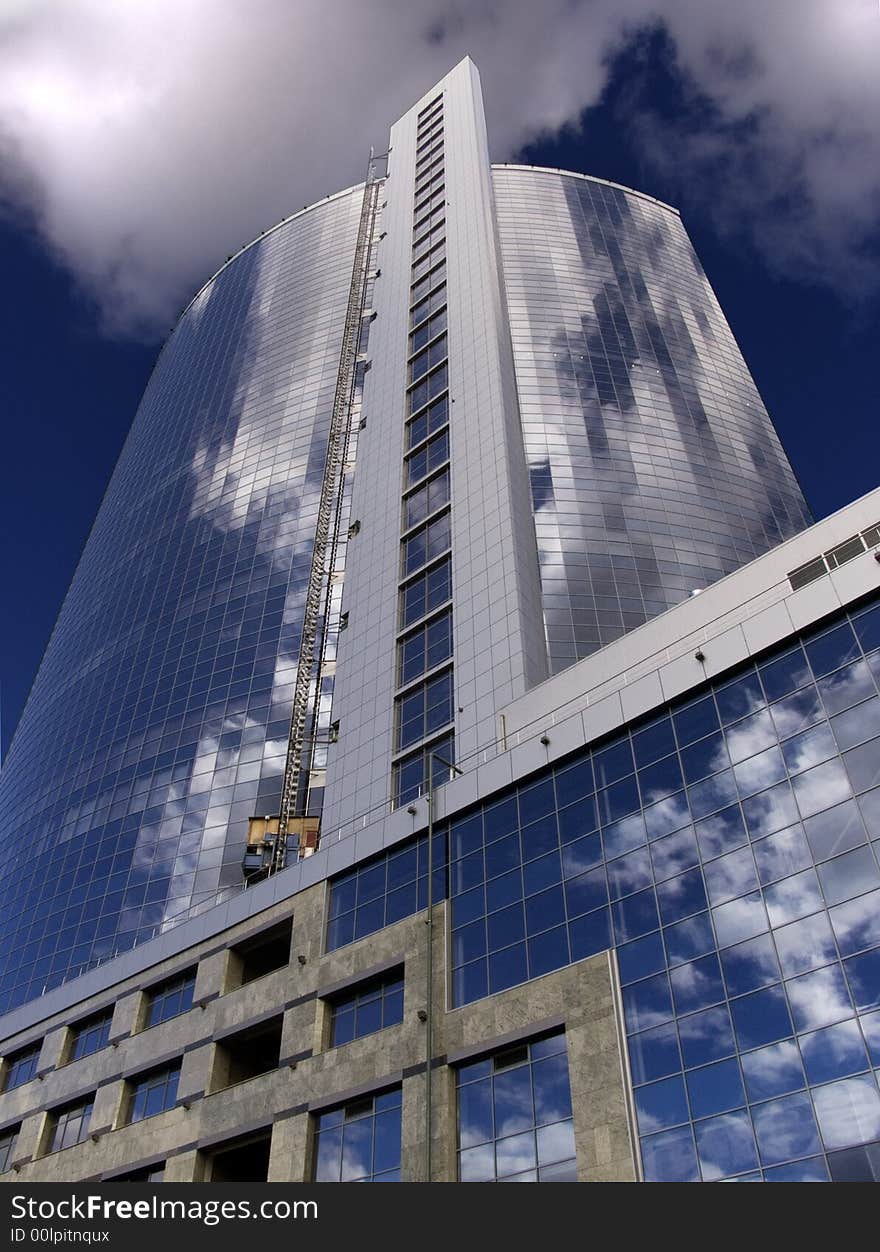 High-altitude building with mirror windows in which the blue sky and white clouds is reflected. High-altitude building with mirror windows in which the blue sky and white clouds is reflected.