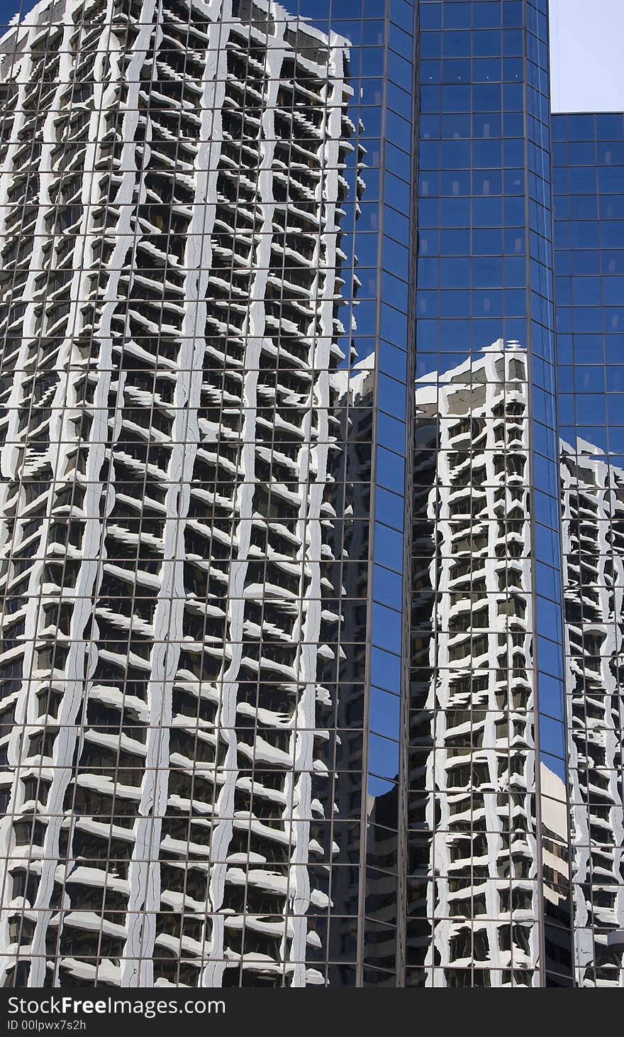 A mirrored building reflects blue sky and the modern office towers across from it. A mirrored building reflects blue sky and the modern office towers across from it.