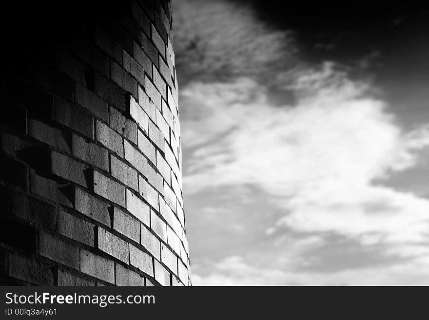 A curved brick wall against a soft cloudy sky. A curved brick wall against a soft cloudy sky.