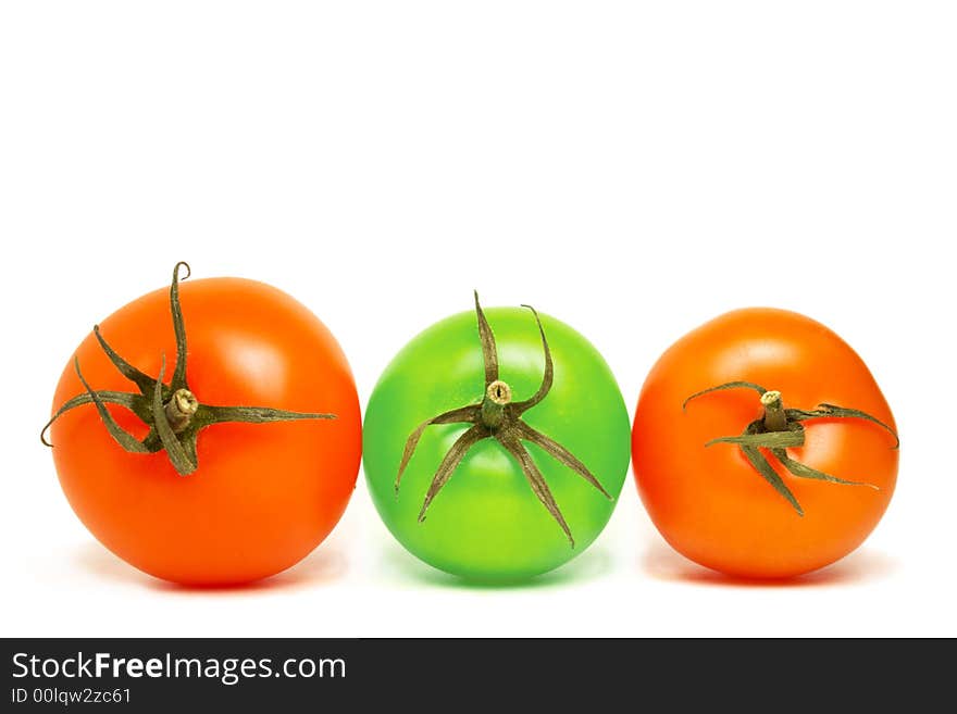 Three top viewed tomatoes lying on the same plane on white background . two of them are red while the middle one is green. Three top viewed tomatoes lying on the same plane on white background . two of them are red while the middle one is green.