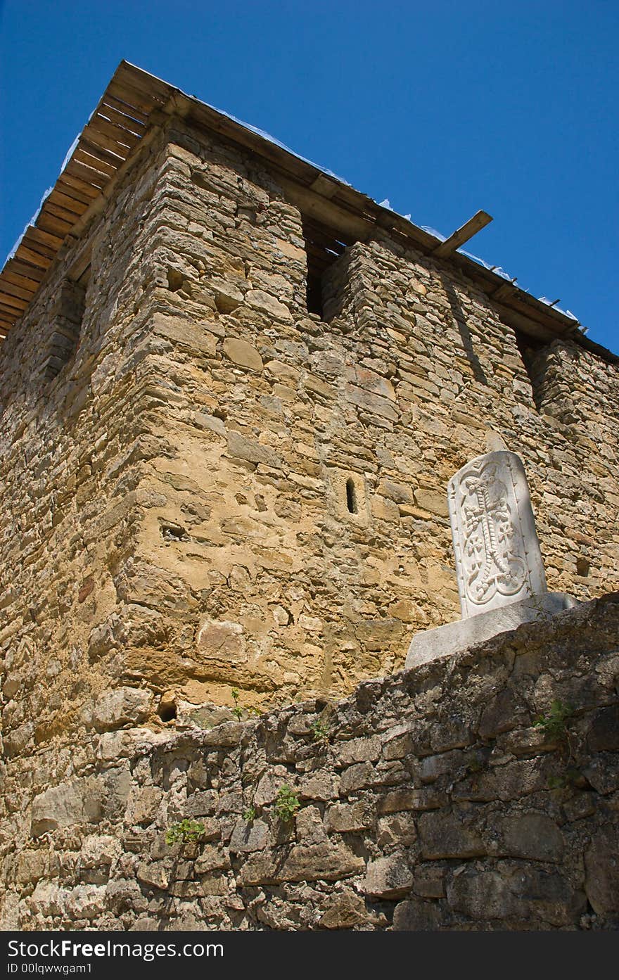 Stone cross bas-relief on temple wall on blue sky background