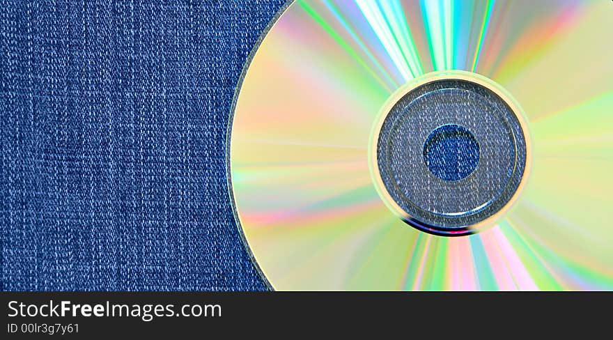 Raibow compact disk over blue jean background. Raibow compact disk over blue jean background