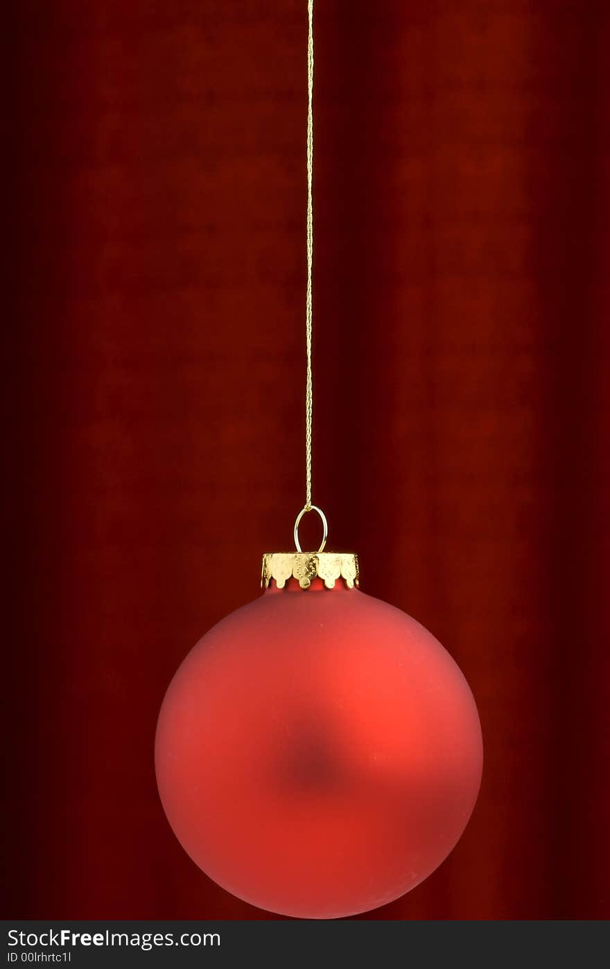 An image of a red Christmas ornament on a burgundy background