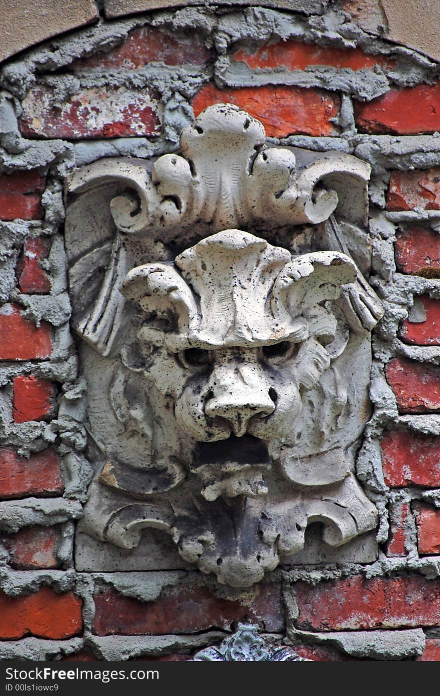 A stone lion looking out from brick wall