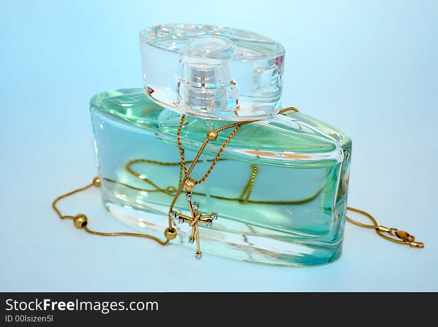 Bottle of perfume and jewels isolated on the blue.