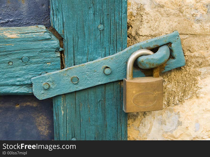 Old lock with a metal clasp on a blue wooden door frame