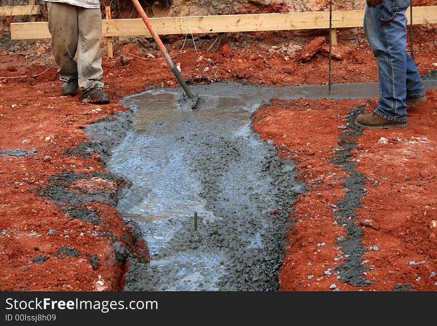 Worker setting footer on new home construction site with plans