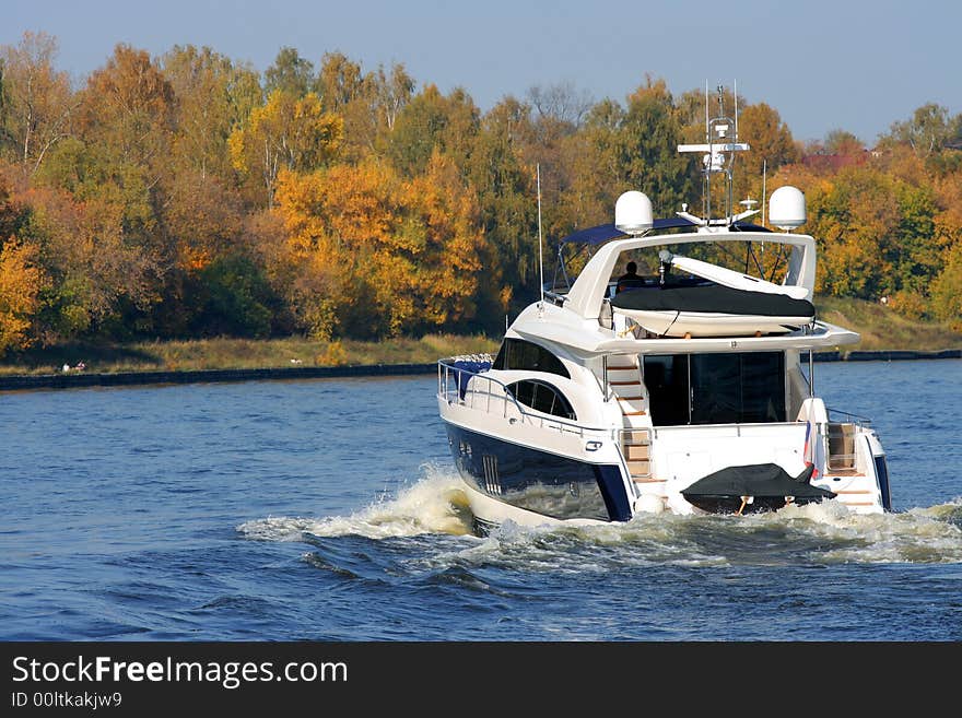 Rear view of sailing luxury yacht on golden autumn scenic background.