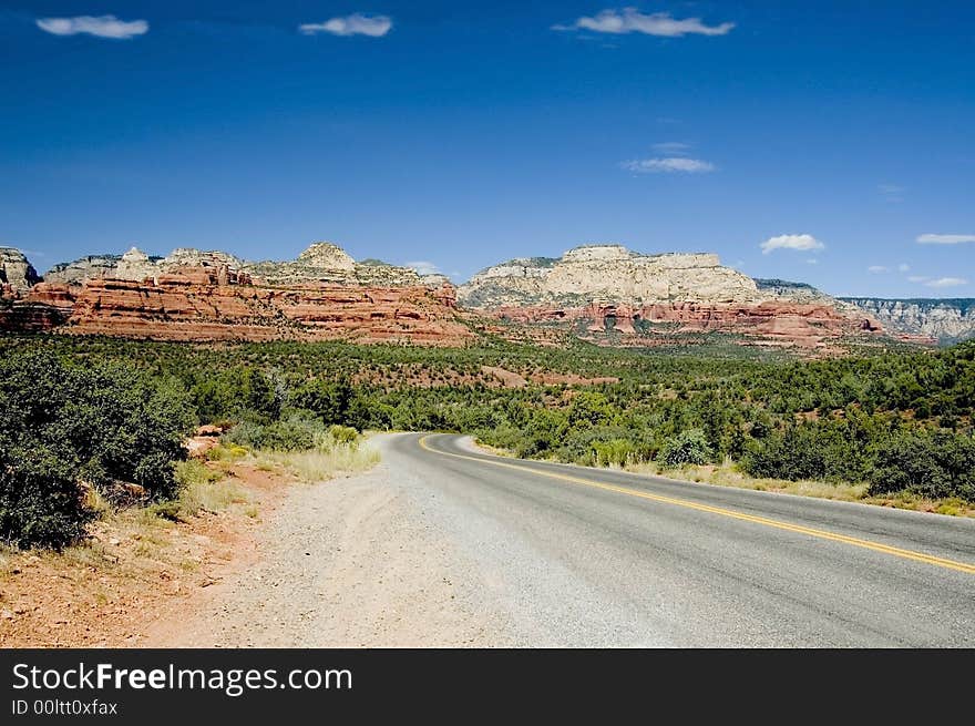 A picture of a highway leading to the mountains of sedona in the background. A picture of a highway leading to the mountains of sedona in the background