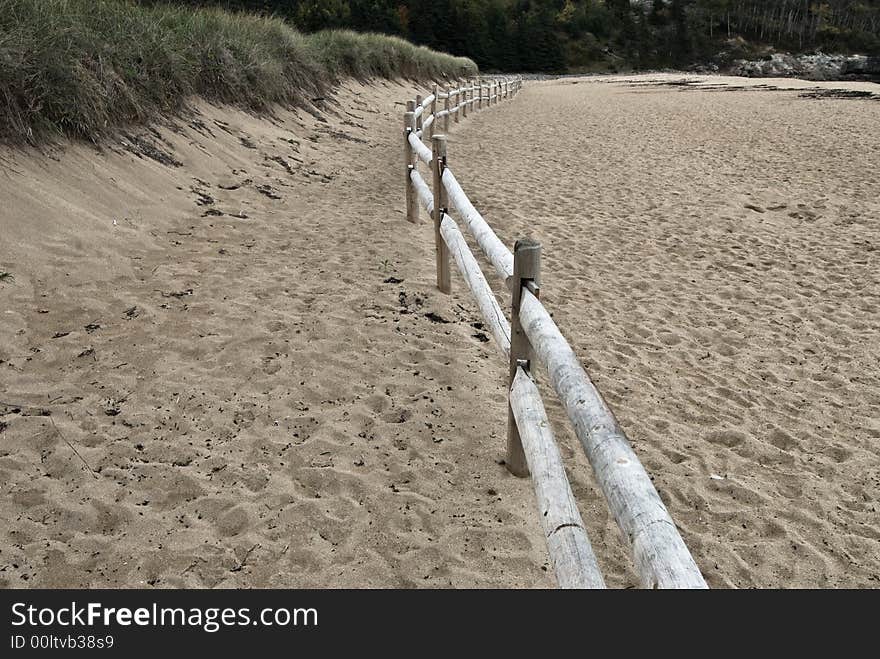 Wooden fence waving through a sandy beach among sand dunes. Wooden fence waving through a sandy beach among sand dunes