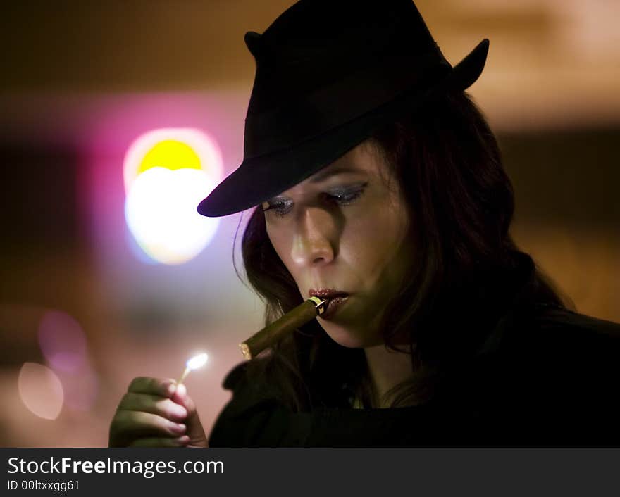 Woman in a fedora lighting a cigar with a match. Woman in a fedora lighting a cigar with a match.