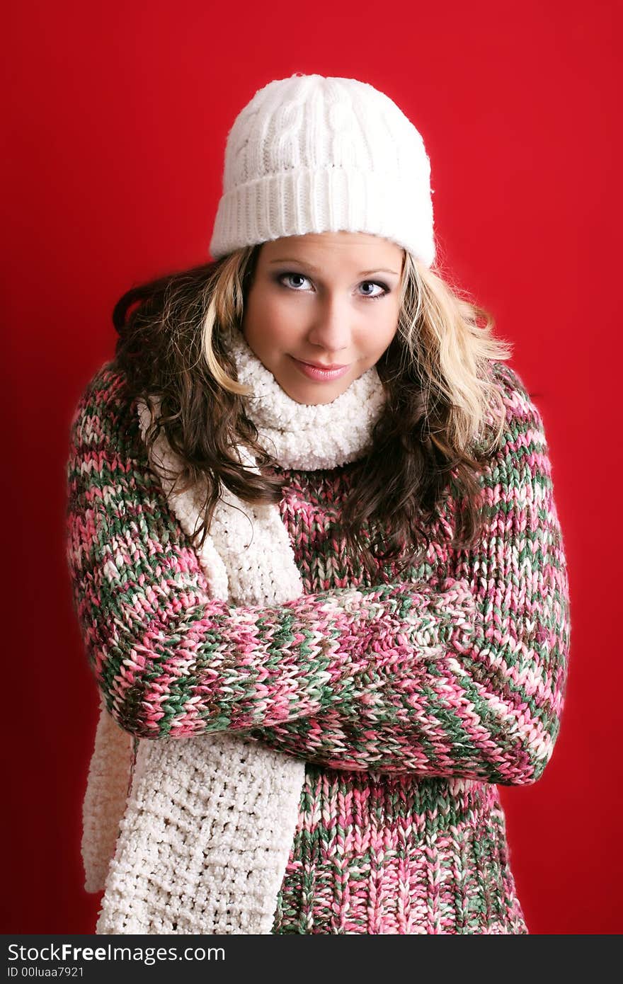 Winter portrait of a beautiful young woman is freezing with a cap and a scarf. Winter portrait of a beautiful young woman is freezing with a cap and a scarf