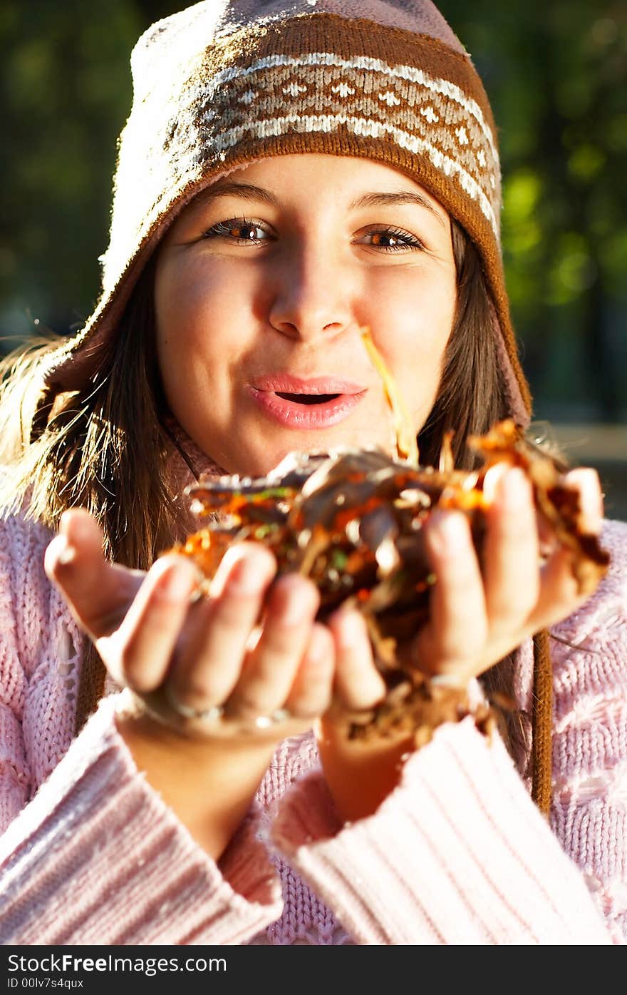 Beautiful young girl blowing golden leaves towards camera. Beautiful young girl blowing golden leaves towards camera