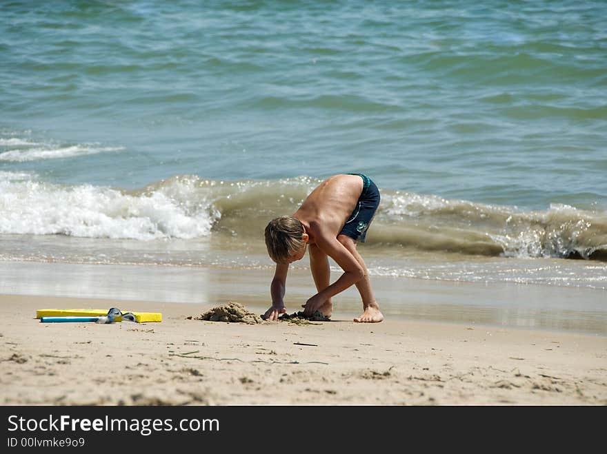 Boy playing in the sand at the ocean. Boy playing in the sand at the ocean.