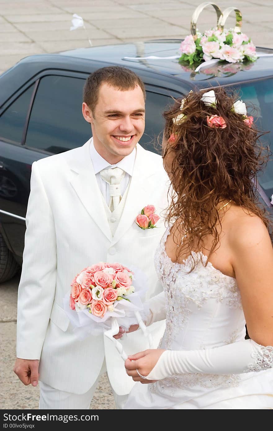 Young couple in wedding wear with bouquet of roses. Young couple in wedding wear with bouquet of roses.