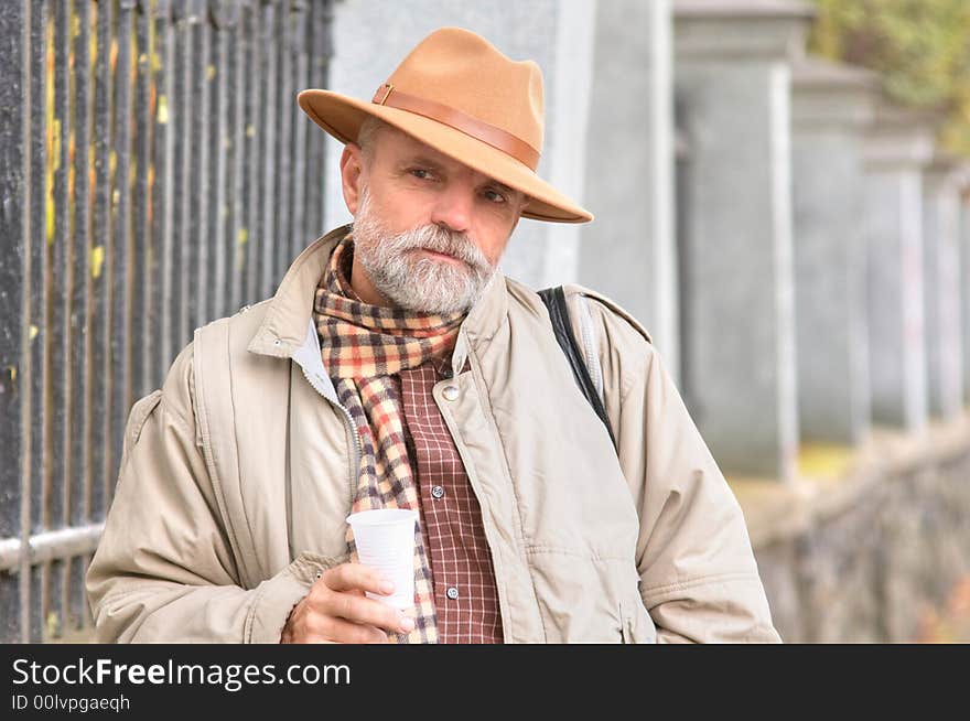 Bearded man in a hat with a plastic glass