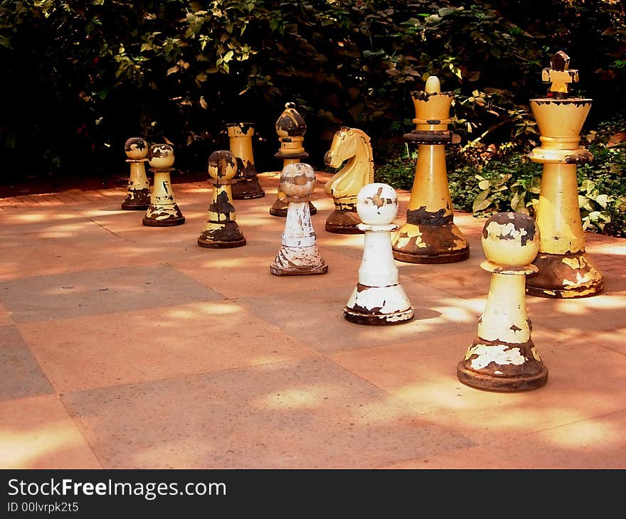 An ancient and ruined pieces of wooden chessmen placed outdoors. An ancient and ruined pieces of wooden chessmen placed outdoors.