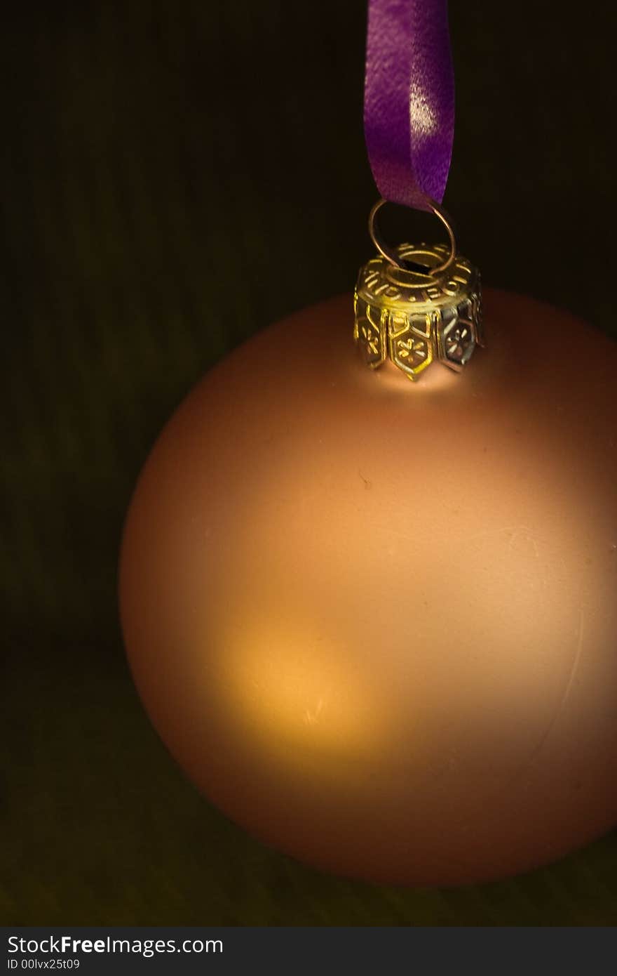 Golden christmas bauble in a dark setting. Golden christmas bauble in a dark setting