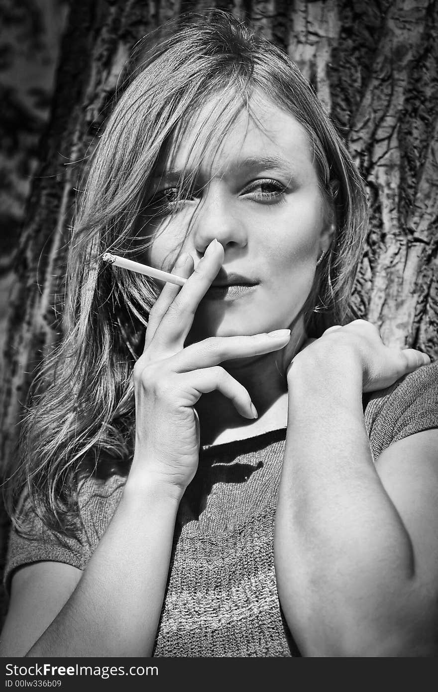 Blond smoking girl against the tree background