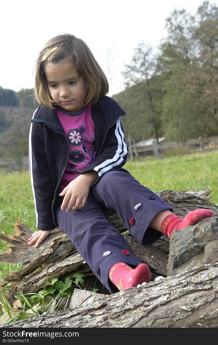 Sad little girl sits alone on a lawn