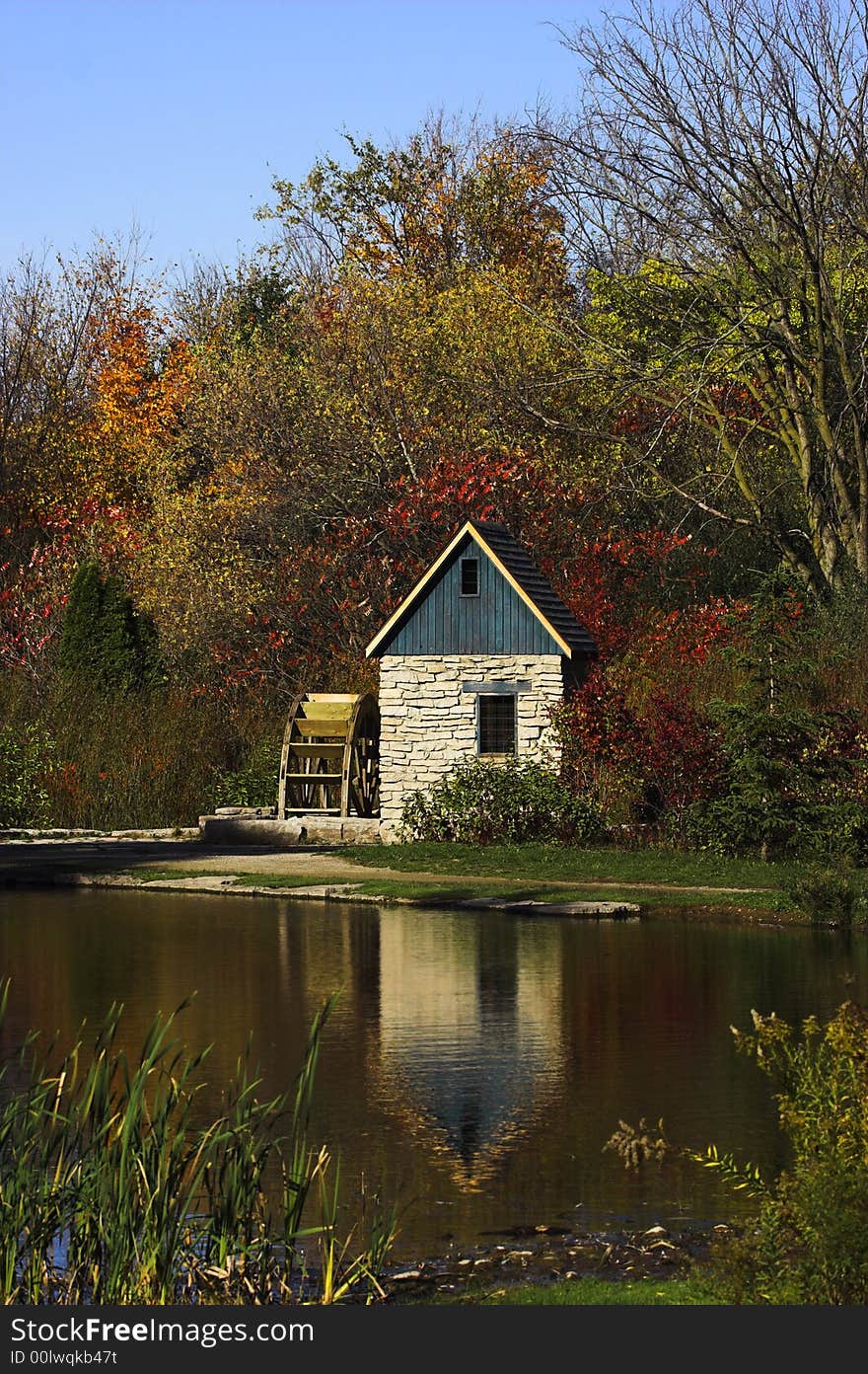 Stone watermill beside a pond during the autumn season.