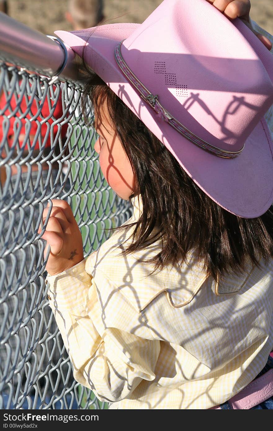 Little cowgirl hanging out by a chain fence. Little cowgirl hanging out by a chain fence