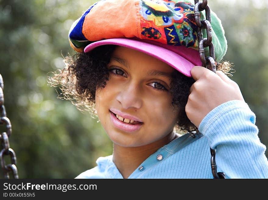 Image of a biracial girl on a swing and backlit by the sun. Image of a biracial girl on a swing and backlit by the sun