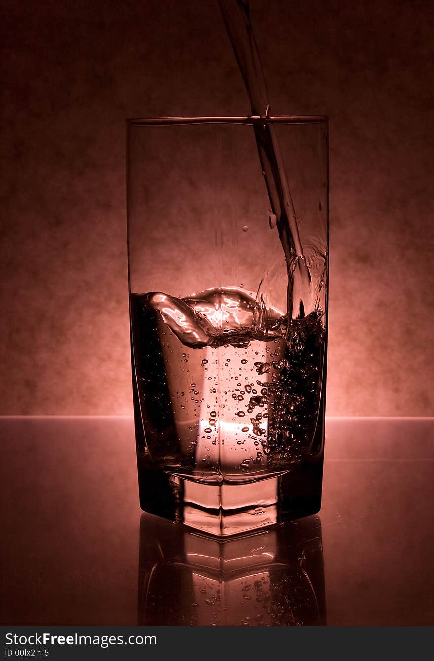 Luquid being poured into the glass on red background. Luquid being poured into the glass on red background.