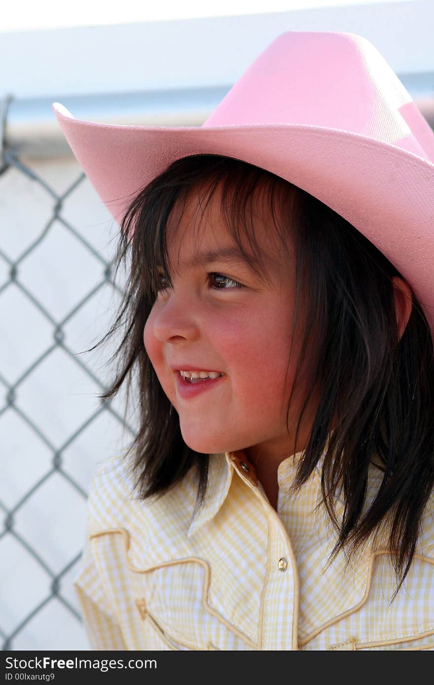 Little cowgirl hanging out by a chain fence. Little cowgirl hanging out by a chain fence