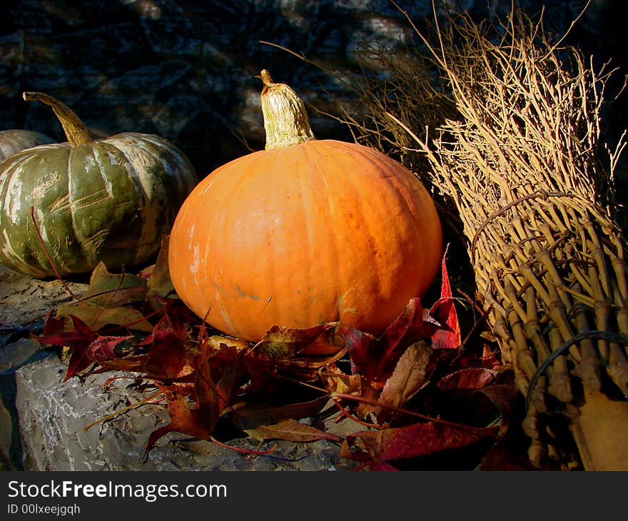 A green and an orange pumpkin with a broom. A green and an orange pumpkin with a broom