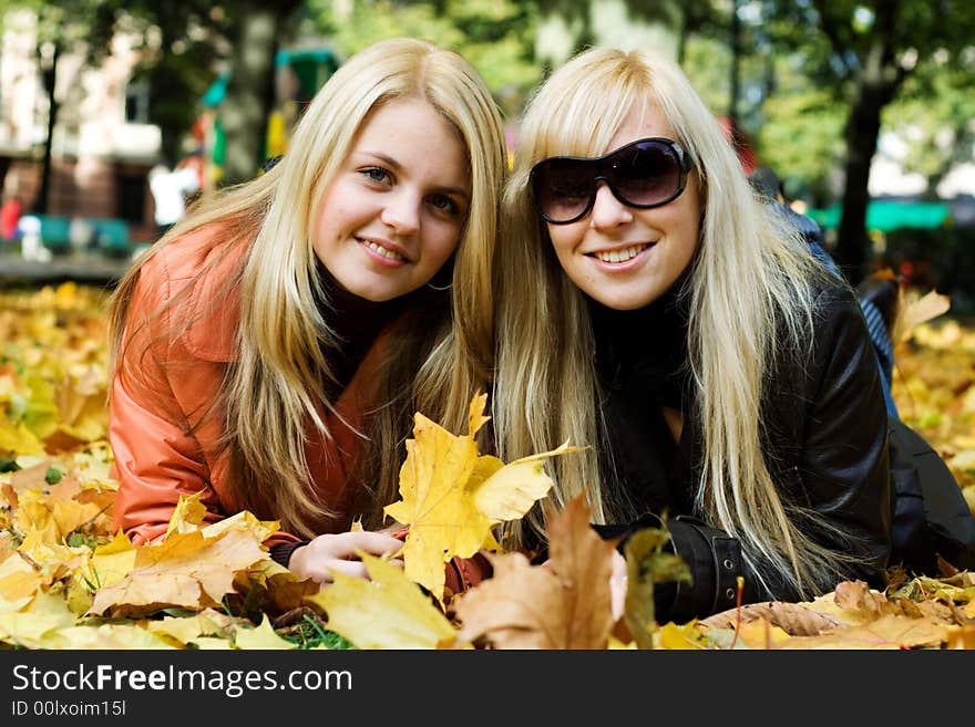 Cute blonde girls on leafs looking and smiling at camera. Cute blonde girls on leafs looking and smiling at camera.