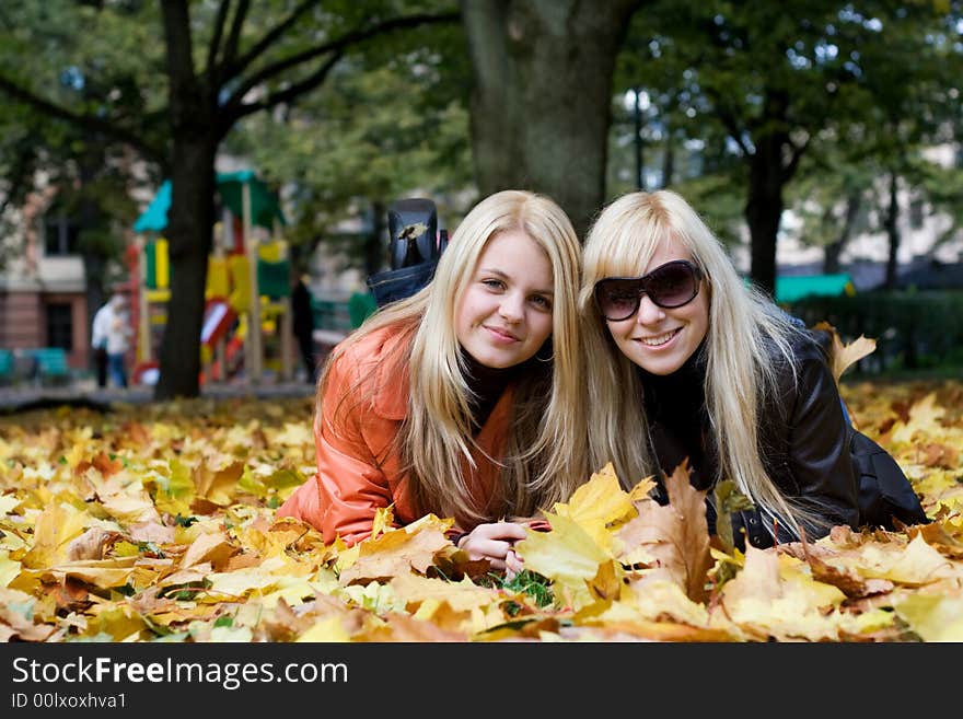 Cute blonde girls on leafs in park. Cute blonde girls on leafs in park.