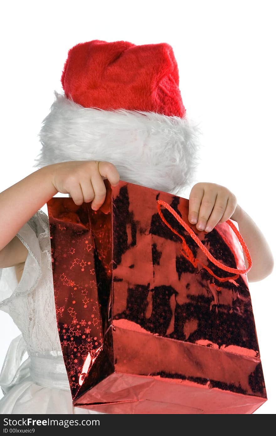 Baby in red santa hat looking in red packege gift over white background