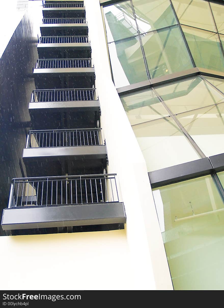 Stairwell painted black with black railings in a modern building whose design is based on a cube that is fractured into many fitting fragments not unlike a 3D jigsaw puzzle. Stairwell painted black with black railings in a modern building whose design is based on a cube that is fractured into many fitting fragments not unlike a 3D jigsaw puzzle.