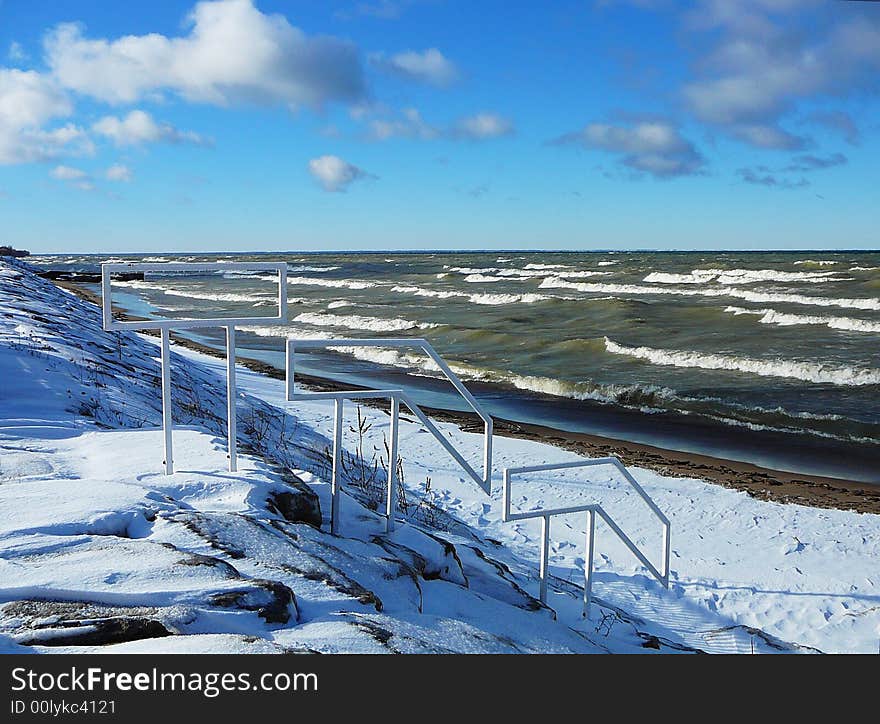 An ice covered shoreline with waves crashing in the background. An ice covered shoreline with waves crashing in the background.