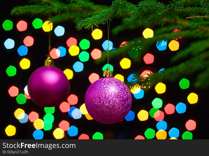 Christmas spheres hang on a fur-tree on a background of a color garland