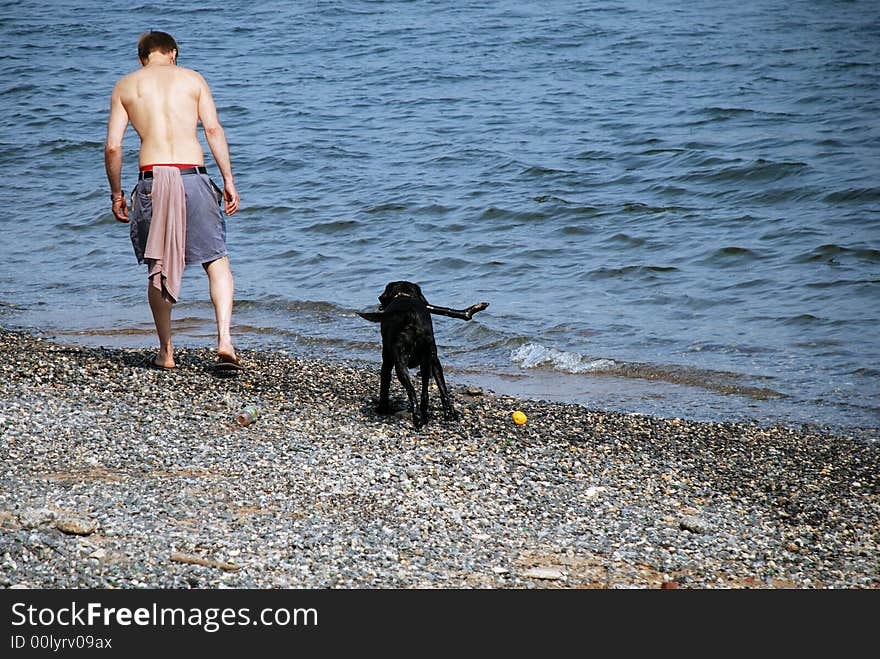 A man on a rocky beach with his dog. A man on a rocky beach with his dog.