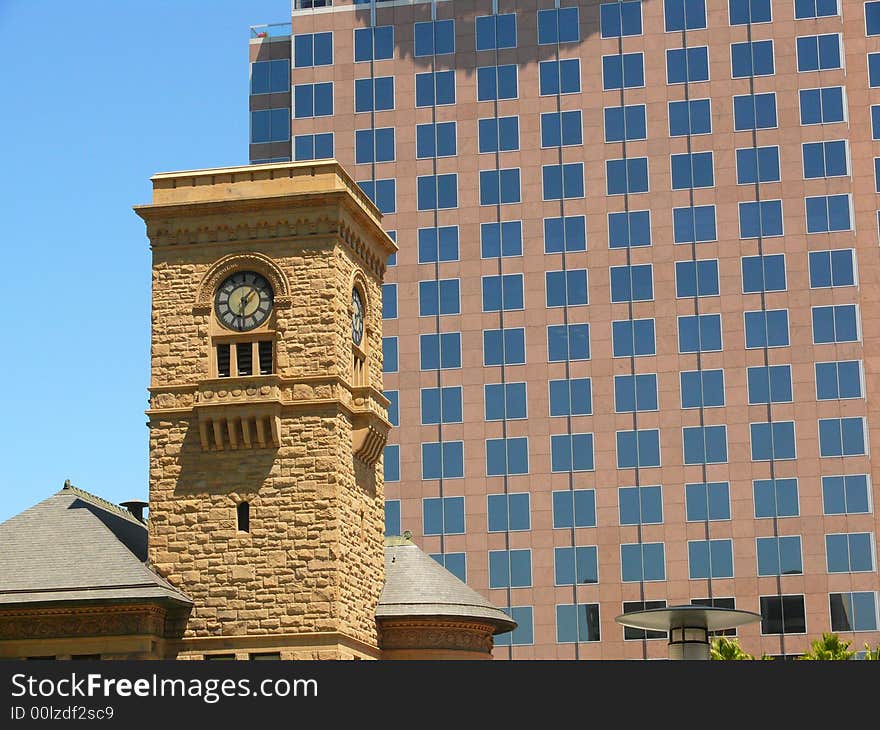 Old and new contrasting in San Jose Downtown. An older stone tower with clock in foreground and a huge modern office building in the background. Old and new contrasting in San Jose Downtown. An older stone tower with clock in foreground and a huge modern office building in the background