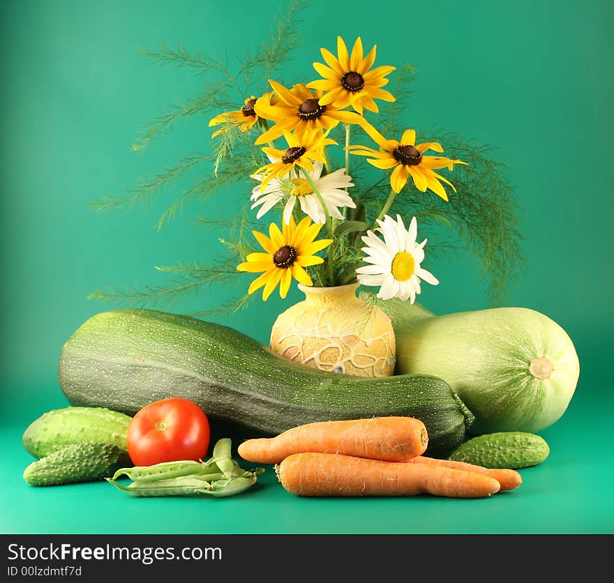 Still-life with vegetables and flowers on a green background.