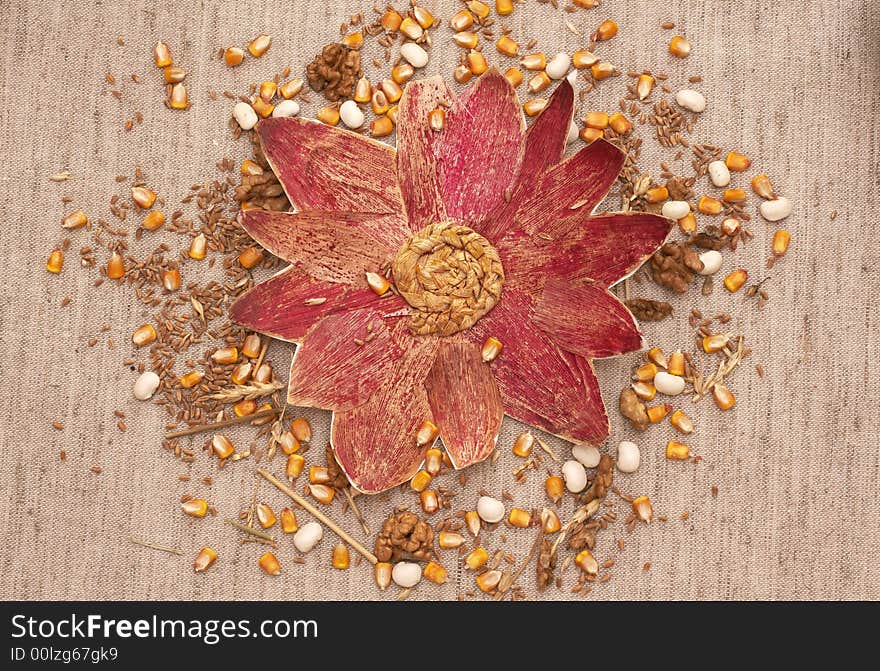 flower made of painted corn leafs and mixed cereals on flax background - autumn bounty and diversity