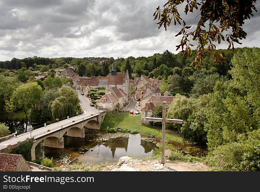 Historic Village in rural France with a road bridge crossing the River and storm clouds above. Historic Village in rural France with a road bridge crossing the River and storm clouds above